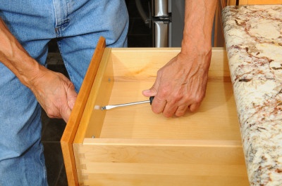 Closeup of a cabinet installer installing drawer hardware on new